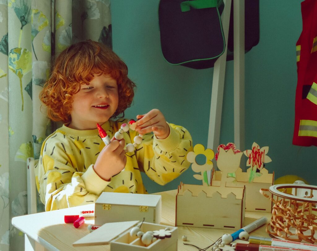 Child in a yellow jumper doing arts and crafts