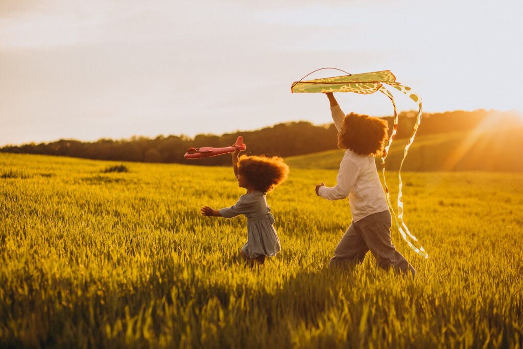 Brother and sister flying a kite in a sunlit field
