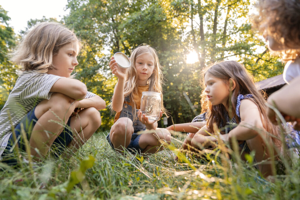 Kids sitting on grass looking for insects