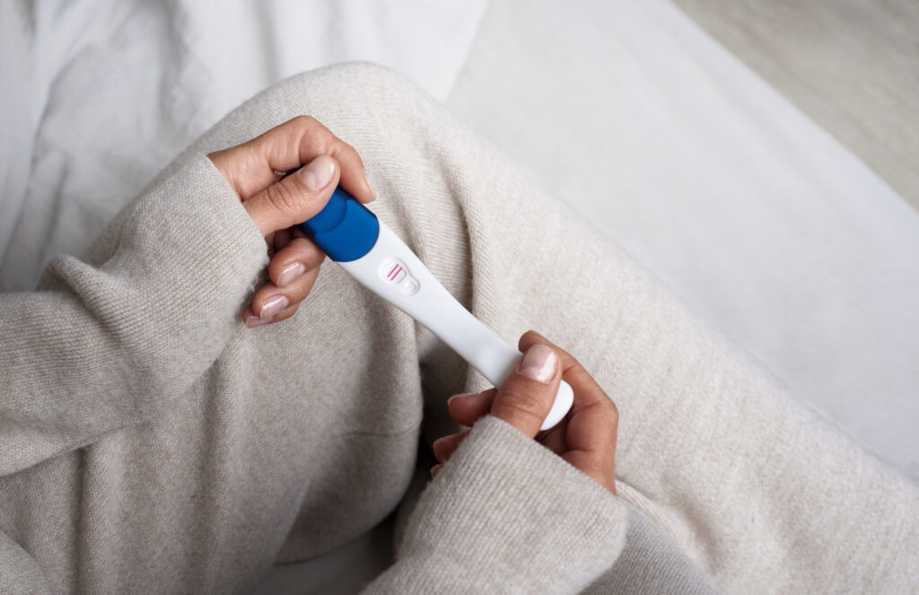 High angle shot of woman holding positive pregnancy test
